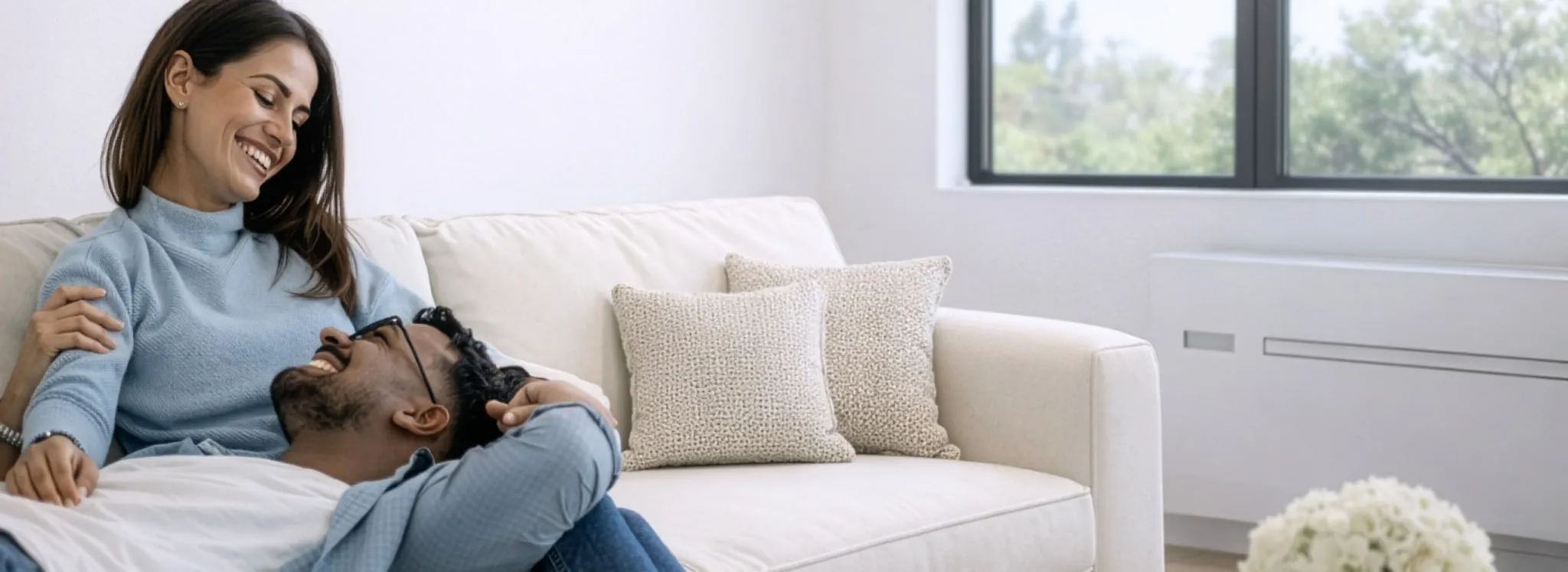 A couple relaxing on a sofa near an AIO wall-mounted unit